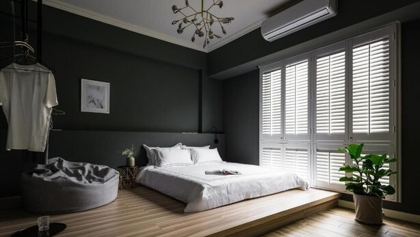 A modern bedroom with a bed, bedside table, and a large window with blinds. - Madam's mansion Homestay (Taitung)