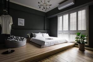 Ein modernes Schlafzimmer mit Bett, Nachttisch und einem großen Fenster mit Jalousien.