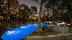 A swimming pool with a curved design, surrounded by trees and modern landscaping. - Siri Nature Roost (Chikkamagaluru)