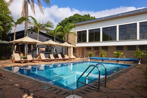 Una piscina al aire libre, sombrillas, sillones reclinables de piscina