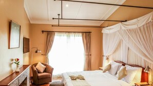 Une chambre d ’hôtel avec un grand lit, un bureau, une chaise et une petite table ronde.