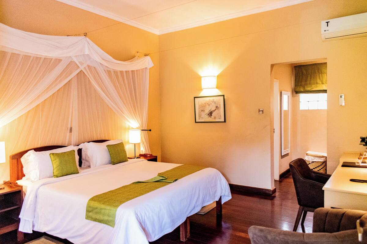 A hotel room with a bed, bedside tables, a desk, and a chair.