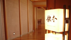 A corridor with wooden flooring and a series of chairs lined up against the wall. - Aeria Tohno (Tono)