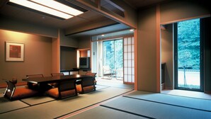 A traditional Japanese-style room with tatami flooring, a low table, and sliding doors leading to a balcony. - Aeria Tohno (Tono)