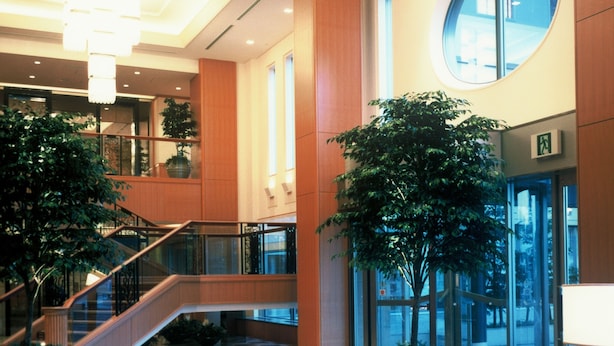 A spacious lobby with a central staircase, multiple seating areas, and large windows offering views of the outside. - Aeria Tohno (Tono)