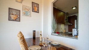 Un comedor con una mesa de madera preparada para dos personas, una botella de vino y dos copas. Hay dos obras de arte sobre café enmarcadas en la pared.