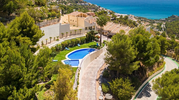 Una propiedad costera con piscina, abundante vegetación y vista al mar.