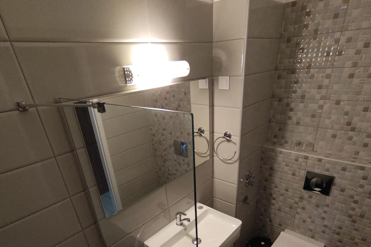 Ein Badezimmer mit Duschkabine, Waschbecken, Toilette und Spiegel.