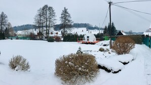 Lumipeitteinen asuinalue, jossa on taloja, aidattu puutarha ja pieni rakennus, jonka katto on lumen peitossa.
