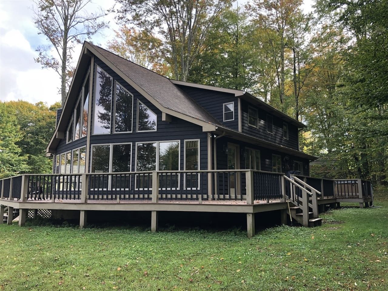 Une maison à deux étages avec une terrasse et de grandes fenêtres.