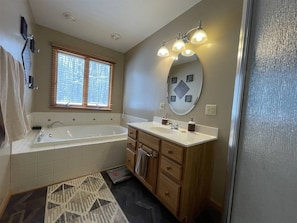 A bathroom with a bathtub, vanity, and a mirror.