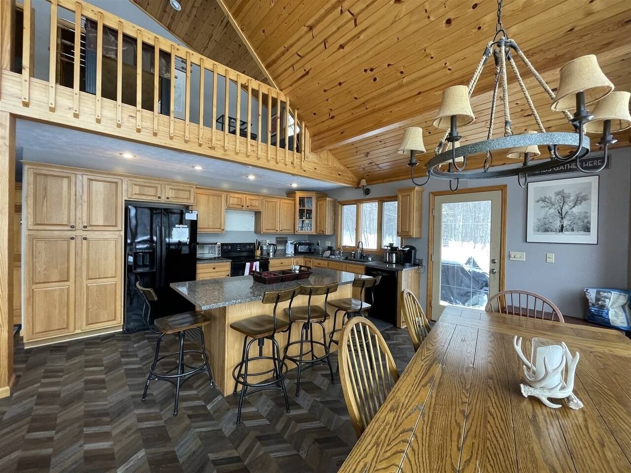 A spacious kitchen with wooden cabinets, a large island with bar stools, and a dining table with chairs.