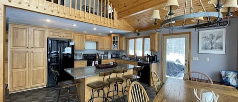 A spacious kitchen with wooden cabinets, a large island with bar stools, and a dining table with chairs.
