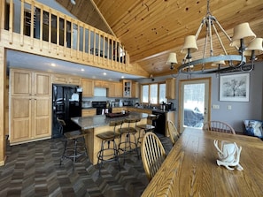 A spacious kitchen with wooden cabinets, a large island with bar stools, and a dining table with chairs.