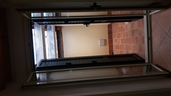 An open doorway leading to a room with a tiled ceiling and a small window.