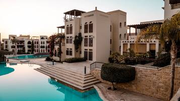 A hotel with a swimming pool, multiple buildings, and a stone pathway leading to the pool.