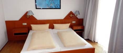 A double bed with two pillows, wooden headboard, nightstands with lamps, and a painting on the wall.