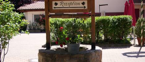 A reception sign with a directional arrow, a stone base, and potted plants.