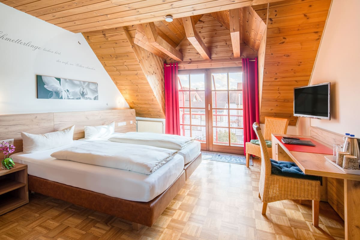 A bedroom with a wooden ceiling, a bed, a desk, and a TV.