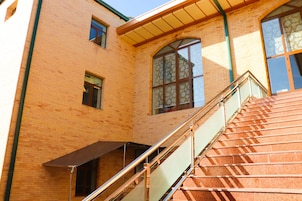 A staircase with glass railings leading to a building with brick walls and large windows.