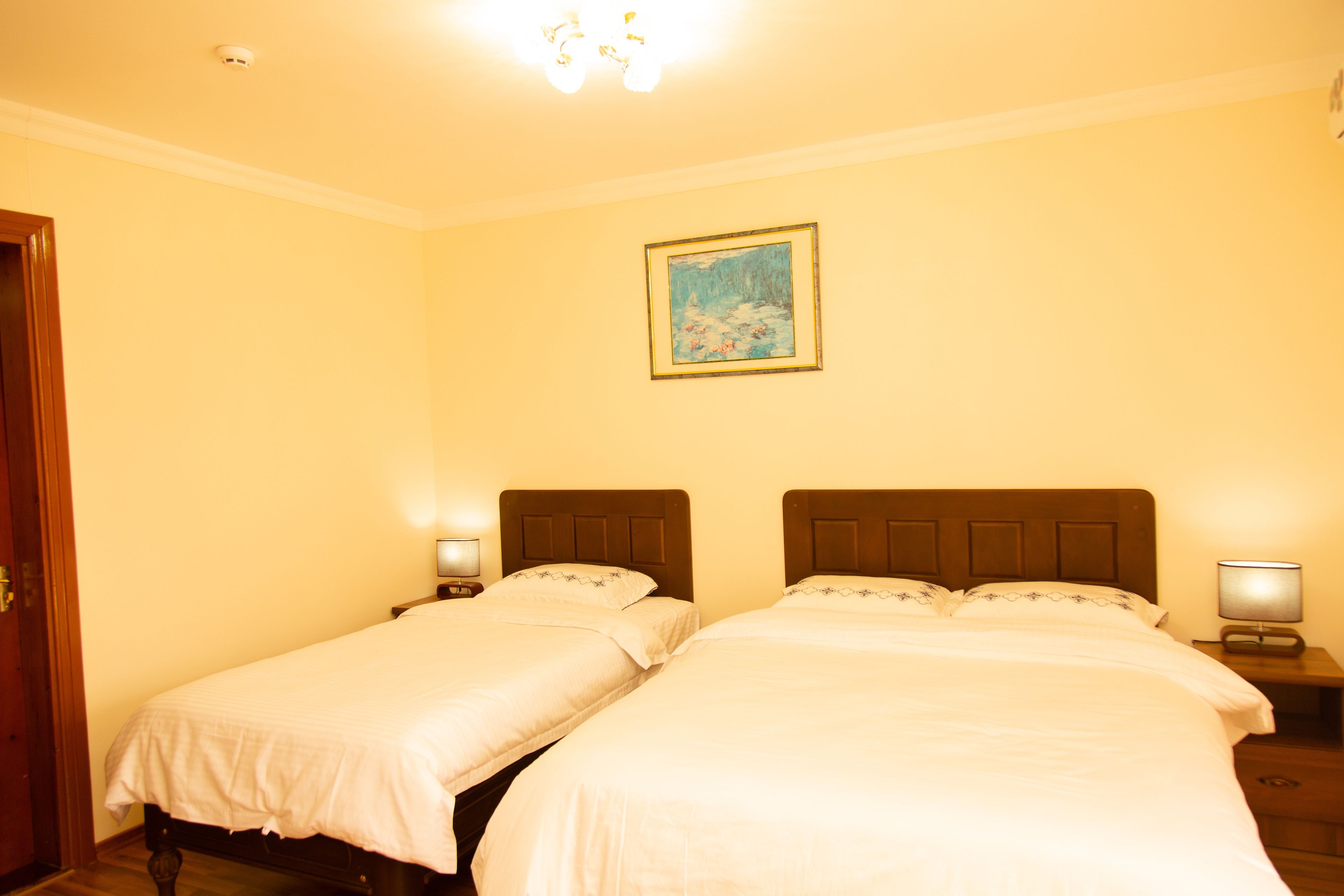 Una habitación de hotel con dos camas individuales, un cuadro en la pared y lámparas de noche.