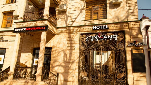 A hotel entrance with ornate iron gates and a sign for 'Hotel Cinzano Complex'.