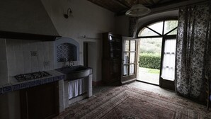 A kitchen with a gas stove, a sink, and a window leading to a garden.
