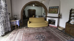 A cozy living room with a yellow sofa, a fireplace, and a large rug.