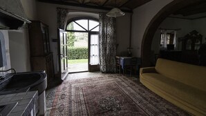 A rustic room with a large window, a sofa, a table, and a kitchen area.