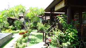 A traditional wooden house with a tiled roof, surrounded by lush greenery and a well-maintained garden. - Perdana Lembongan (Lembongan Island)