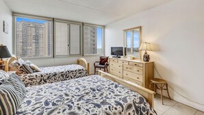 A bedroom with two beds, a dresser, a chair, a television, and a window with a city view. - DAILY ACTIVITIES & LINENS INCLUDED*! Seventh floor, 2 bedroom, 2 bath condo one back from ocean. (Ocean City)
