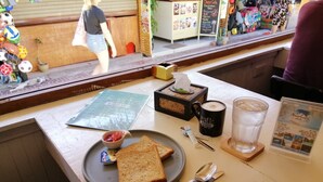 A breakfast table with toast, a mug, a glass of water, and a menu. - neverland hostel dorm in phi phi. (Koh Phi Phi)