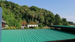 A building with a green roof, surrounded by lush greenery and palm trees. - neverland hostel dorm in phi phi. (Koh Phi Phi)