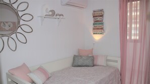 A bedroom with a bed, pillows, a wall-mounted shelf with decorative items, a mirror, and a motivational poster.