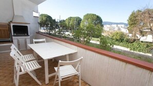 A balcony with a table and chairs, a grill, and a view of a residential area. - M025 - Marcelli, three-room apartment with terrace 200 meters from the sea (Marcelli)
