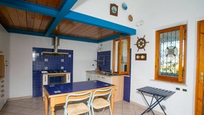 A kitchen with blue tiles, a wooden ceiling, and a dining table with chairs. - M025 - Marcelli, three-room apartment with terrace 200 meters from the sea (Marcelli)