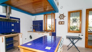 A kitchen with a blue-tiled island, a stove, a washing machine, and a window with a view. - M025 - Marcelli, three-room apartment with terrace 200 meters from the sea (Marcelli)
