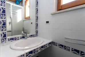 A bathroom with a white sink, blue and white patterned tiles, a mirror, and a towel rack. - M025 - Marcelli, three-room apartment with terrace 200 meters from the sea (Marcelli)