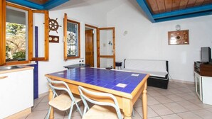 A room with a wooden ceiling, a tiled table, a bed, and a TV. - M025 - Marcelli, three-room apartment with terrace 200 meters from the sea (Marcelli)