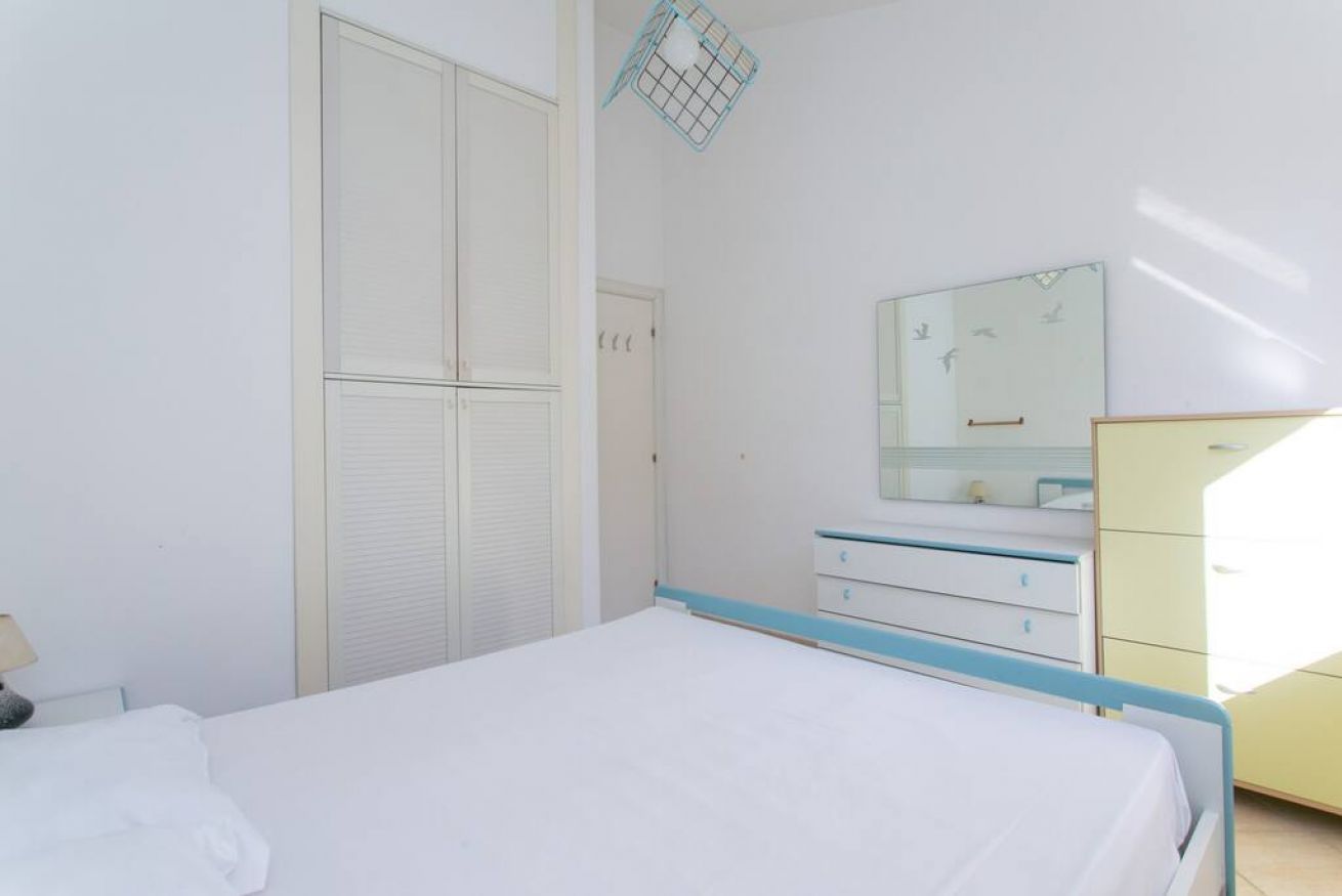 A bedroom with a bed, a dresser, a mirror, and a wardrobe.
