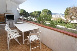 A balcony with a table and chairs, a grill, and a view of a residential area. - M025 - Marcelli, three-room apartment with terrace 200 meters from the sea (Marcelli)