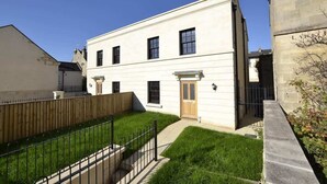 Un bâtiment à deux étages, doté d’un toit plat, d’une clôture en bois et d’une allée pavée.