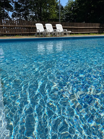 Una piscina al aire libre de temporada, sillones reclinables de piscina