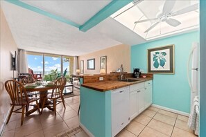 Una cocina con isla de madera, armarios blancos y vistas al exterior.