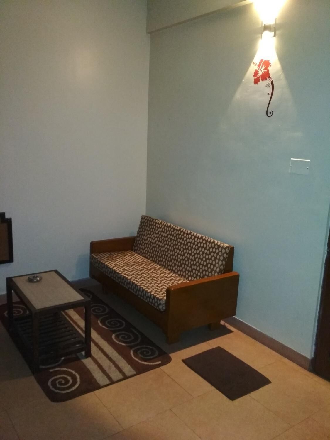 A small living area with a sofa, a small table, and a rug.