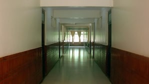 A long, narrow hallway with wooden paneling on the walls and a tiled floor. - Hotel Durvankur (Ratnagiri)