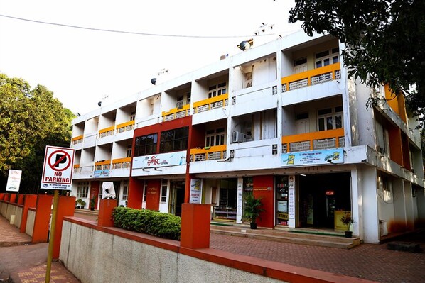 Un edificio de varios pisos con un letrero de 'No Estacionar', múltiples balcones y diversas tiendas.