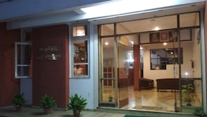 A hotel entrance with a glass door, potted plants, and a visible interior with a sofa and a dining area. - Hotel Durvankur (Ratnagiri)