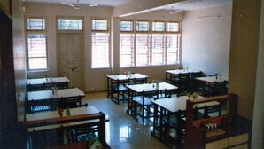 A classroom with multiple desks and chairs, large windows, and ceiling fans. - Hotel Durvankur (Ratnagiri)