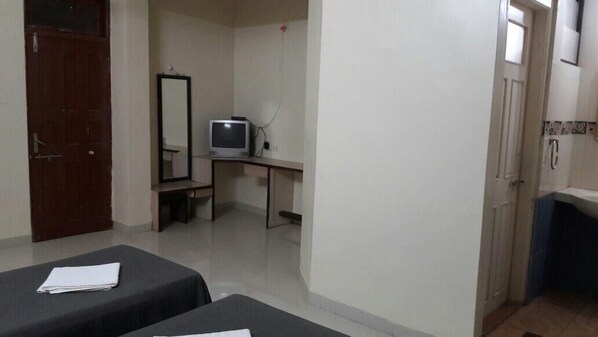 A room with two beds, a desk, a television, and a mirror. - Hotel Durvankur (Ratnagiri)